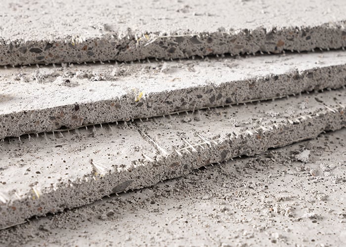 Stacked gray cement backer board sheets with rough textured edges shown close-up for product comparison.