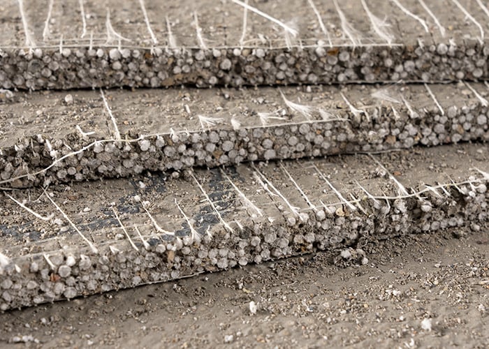Image showing a close-up of fiber cement backer board material with layered edges and surface texture for comparison against another backer board.